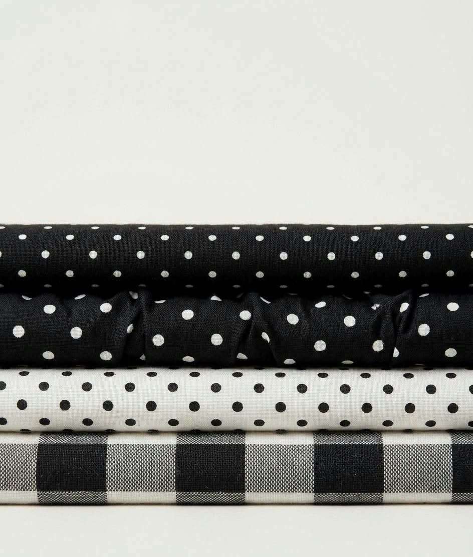 Four folded fabrics stacked: black polka dot, black large polka dot, white polka dot and black-and-white gingham