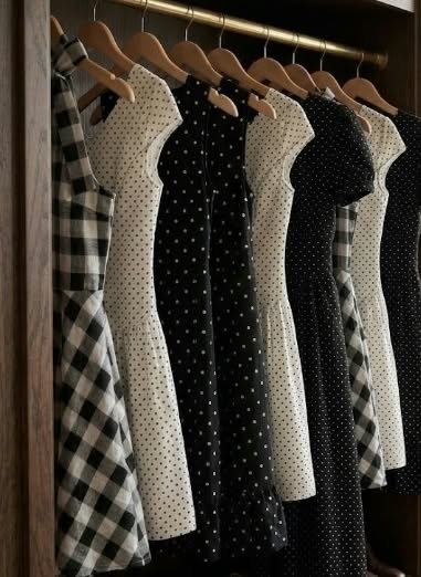 Polka dot and gingham dresses hanging on wooden hangers in a wardrobe